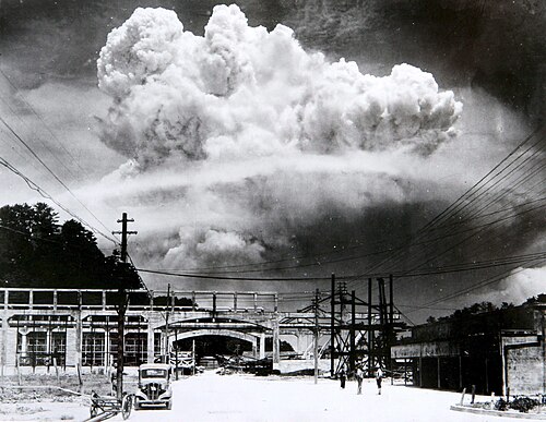 A towering mushroom cloud rising over the city of Nagasaki after the atomic bombing.
