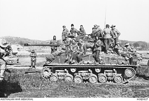 Soldiers riding on top of an M4 Sherman tank during the Korean War.