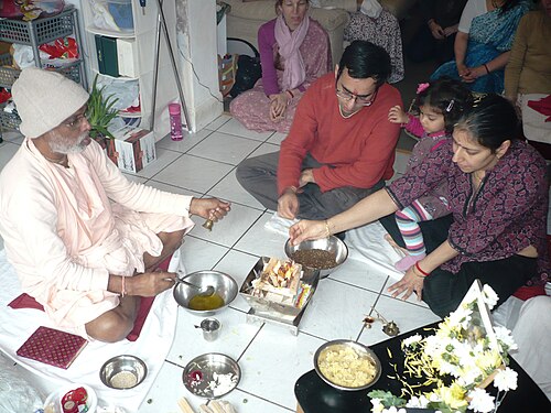 A Hindu family gathered around a home shrine performing puja