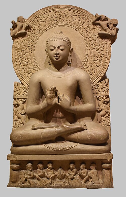 Sandstone sculpture from Sarnath of the Buddha seated, hands in the teaching gesture, with a wheel of Dharma below